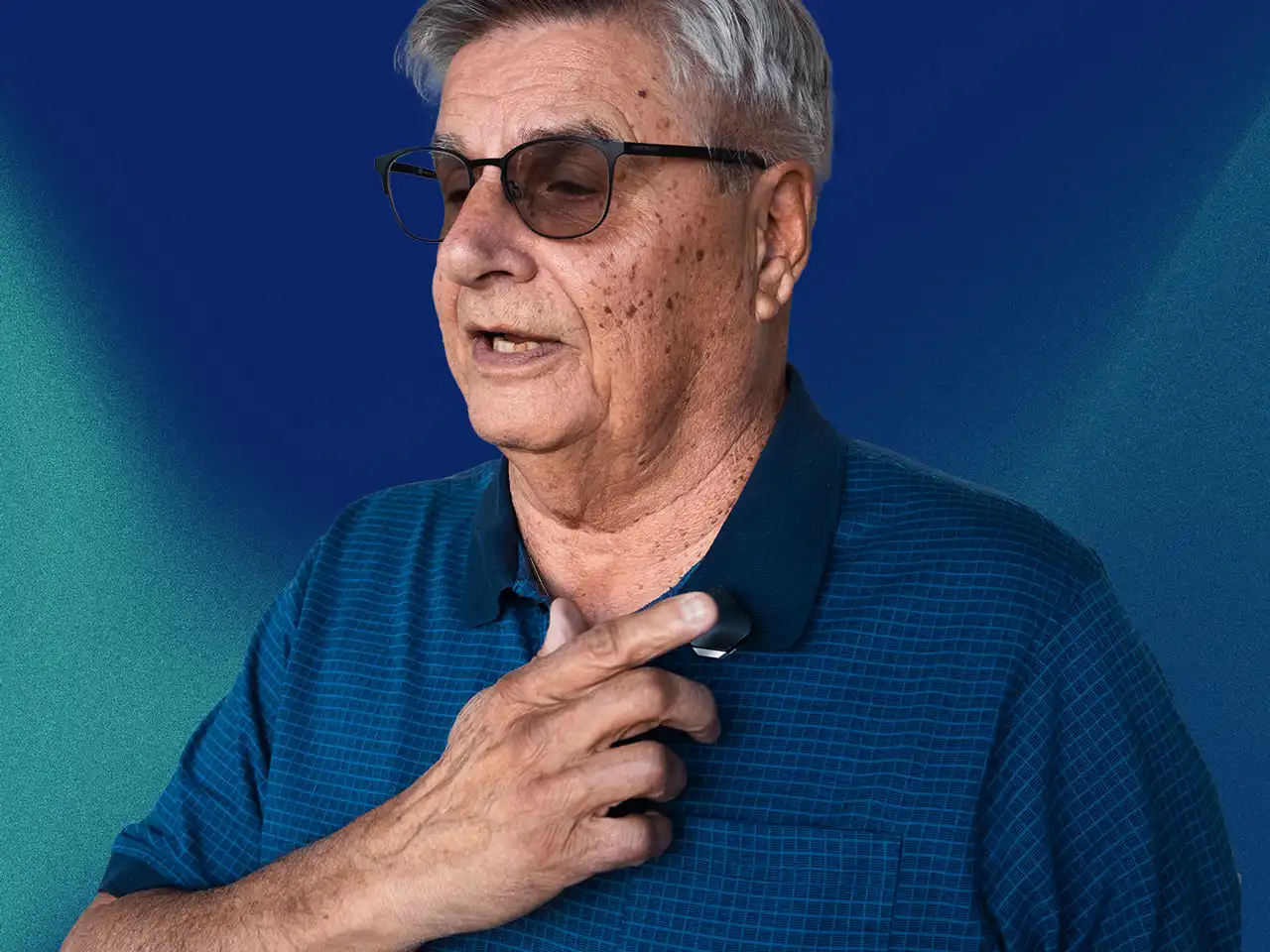A man tapping the MYLL device at his chest and speaking to it